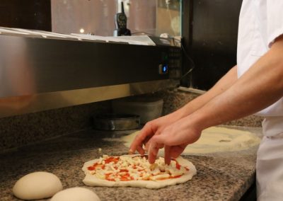 Liebevolle Zubereitung von Hand einer Pizza in Ihrem Restaurant Antica Osteria in München