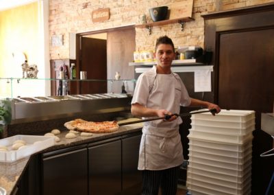 Pizzabäcker des Restaurants Antica Osteria mit einer gebackenen Pizza